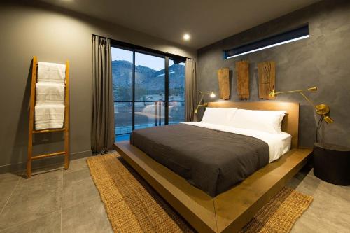 Un dormitorio con una cama grande y una ventana grande. en The Box by Fieldtrip - Architectural Villa w Pool Spa, en Joshua Tree