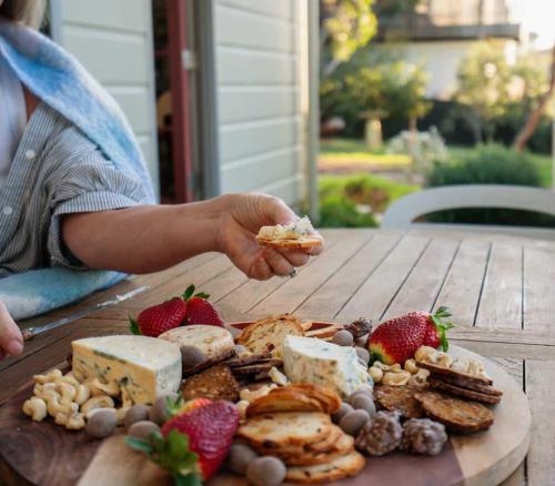a person holding a piece of food on a wooden table at Chiton Cottage by the Sea - Restaurants, Bikes, Pets in Hayborough