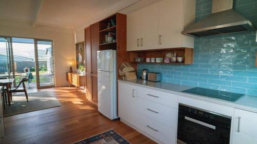 a kitchen with white cabinets and a blue tile wall at Chiton Cottage by the Sea - Restaurants, Bikes, Pets in Hayborough
