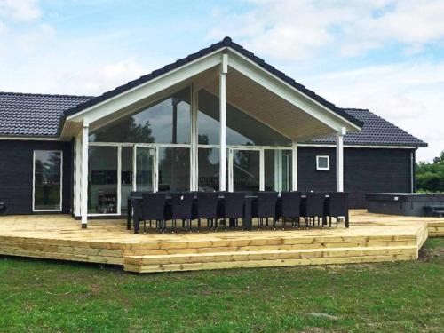 a large deck with black chairs on top of a house at 14 person holiday home in Væggerløse in Marielyst