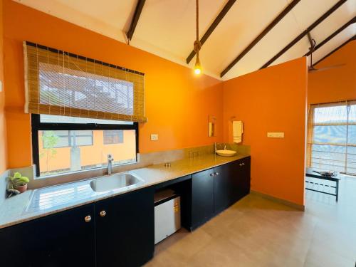 a large kitchen with orange walls and a sink at Heyday by the valley - panchalimedu in Pīrmed