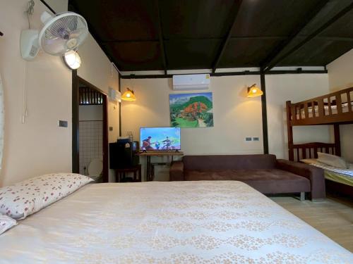 a bedroom with a bed and a couch and a fan at Ashi Guesthouse Chiangdao in Chiang Dao