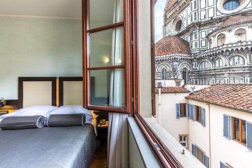 a bedroom with a bed and a view of a building at Hotel Duomo Firenze in Florence