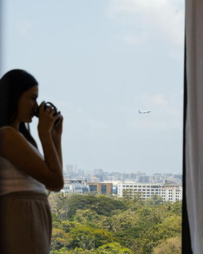 a woman standing in front of a window drinking at Hilton Garden Inn Mumbai International Airport in Mumbai