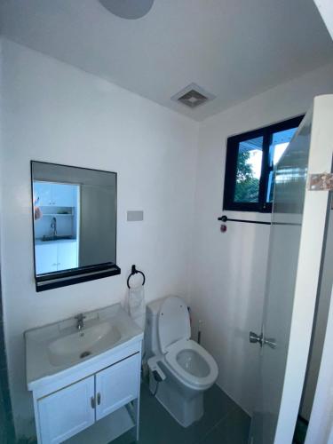 a bathroom with a toilet and a sink and a mirror at JNJ Apartelle in Tacurong