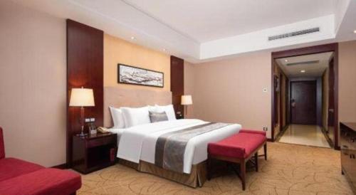 a hotel room with a large bed and a red bench at Wuhan Soluxe Hotel in Wuhan