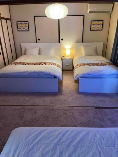 a bedroom with two beds and a light on the wall at Share House on the Hill in Yokohama
