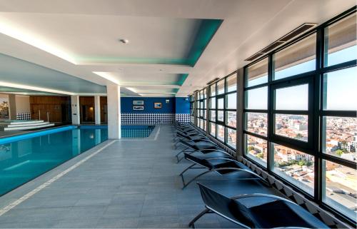 una piscina en un edificio con sillas y ventanas en Vila Gale Porto - Centro, en Oporto