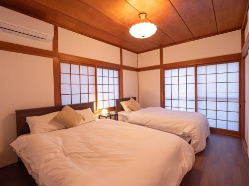 due letti in una stanza con finestre di 高松市の築45年のお家をリノベーションした民泊古都 a Takamatsu