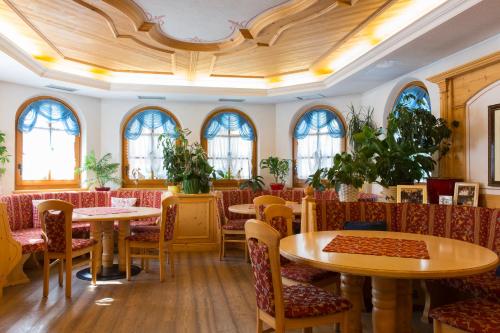 a restaurant with tables and chairs and windows at Hotel Cristina in Pinzolo