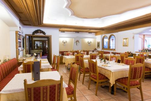 a restaurant with tables and chairs in a room at Hotel Cristina in Pinzolo