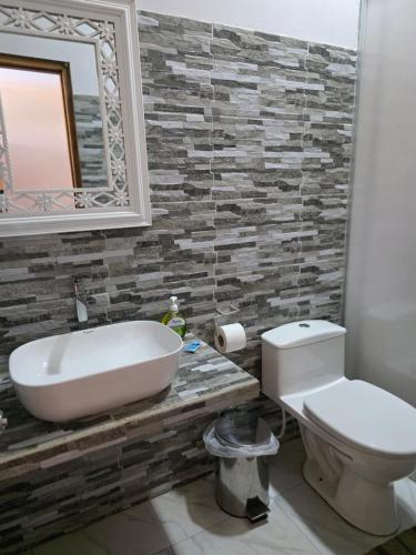 a bathroom with a sink and a toilet and a mirror at Posada Casa Bonita in Puerto Maldonado