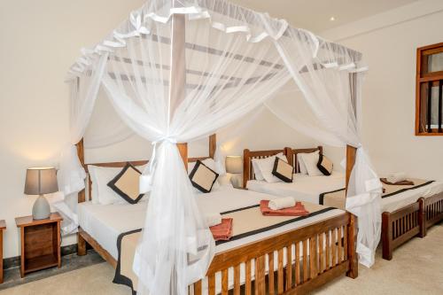 a bedroom with two beds with mosquito nets at Serenity Boutique - Unawatuna in Unawatuna