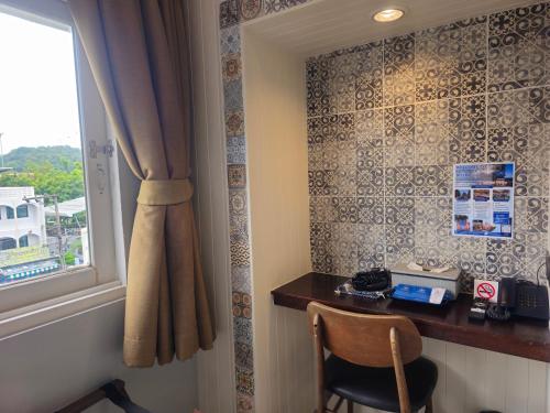 a room with a window and a table with a telephone at Montree Phuket Hotel in Phuket Town