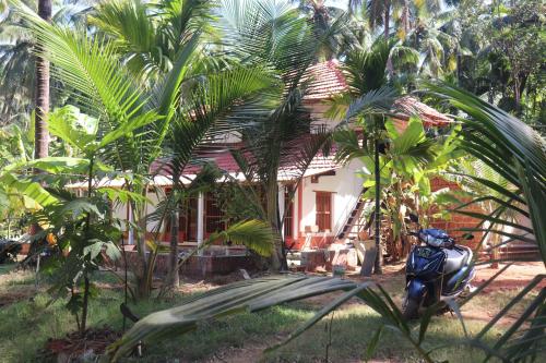 a motorcycle parked in front of a house with palm trees at Veeru River Front Nature Homestay Honnavar in Honāvar