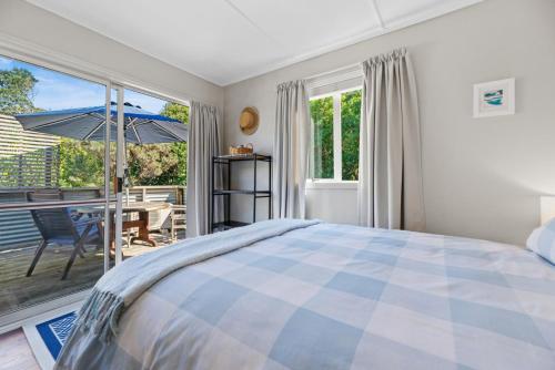 a bedroom with a bed and a patio with an umbrella at The Cottage - Waihi Beach Holiday home in Waihi Beach