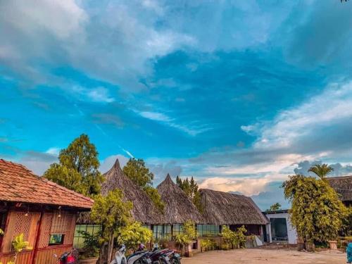 a row of houses with thatched roofs under a blue sky at Homestay Thác Liên Khương in Ðưc Trọng
