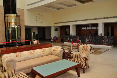 a lobby with two couches and a table and chairs at Hotel Parsons Court in Dindigul