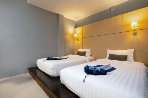 two beds in a hotel room with towels on them at Montree Phuket Hotel in Phuket Town