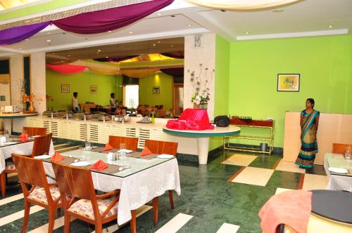 a restaurant with green walls and tables and chairs at Hotel Parsons Court in Dindigul