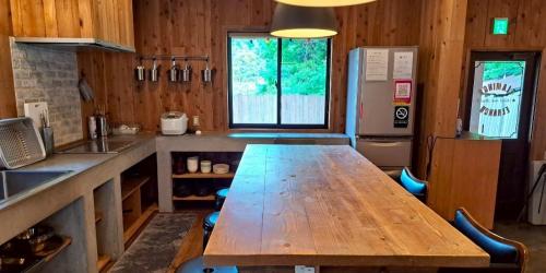 a kitchen with a wooden table and a refrigerator at コテージフラミンゴ in Futtsu
