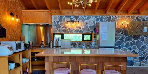 a kitchen with a counter with chairs and a counter top at コテージフラミンゴ in Futtsu