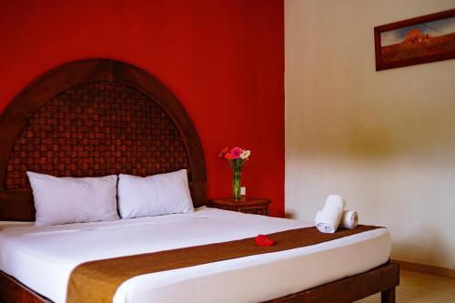 a bedroom with a bed with a red wall at Hotel Tuul in Izamal