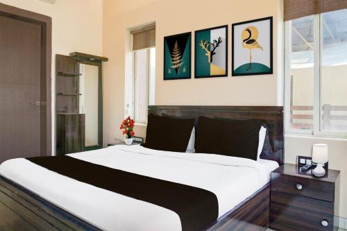 a bedroom with a large white bed and pictures on the wall at Collection O Varsoli Uptown formerly Carmello & Othelo Villas in Lonavala