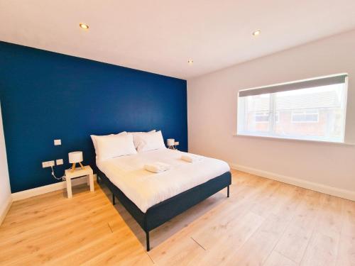 a bedroom with a large bed with a blue wall at 5 star Luxury Home in a Magnificent area -Chester in Hough Green