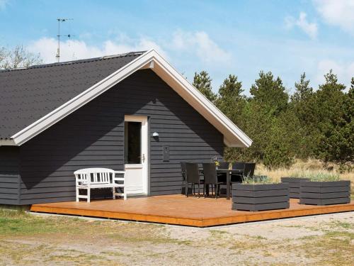 a black house with a deck with chairs and a table at Secluded Retreat in Nature - By Traum Ferienwohnungen in Blåvand