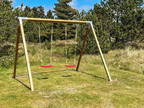 a swing set with three swings in a field at Secluded Retreat in Nature - By Traum Ferienwohnungen in Blåvand