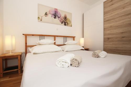 Un dormitorio con una cama blanca con toallas. en Apartment Vista Makarska, en Makarska