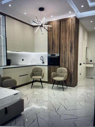 a living room with two chairs and a kitchen at Sea breeze, studio apartment in Nardaran