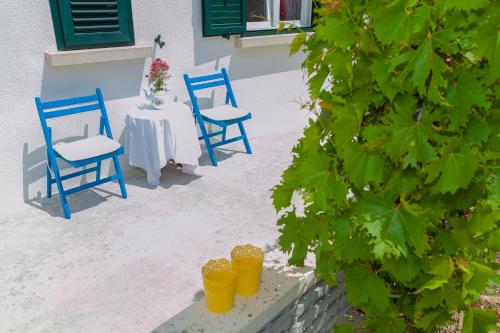 two blue chairs and a table with yellow cups at Villa Lav in Prigradica