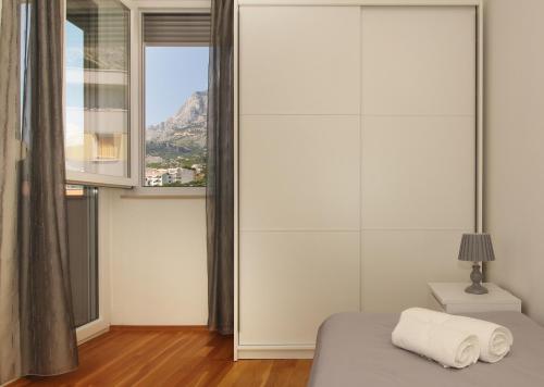 ein Schlafzimmer mit einem Bett und einem großen Fenster in der Unterkunft Apartment Vista Makarska in Makarska