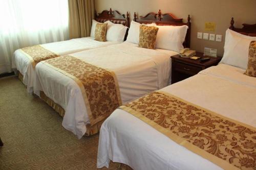a hotel room with three beds with white sheets at Yanji Yanbian International Hotel in Yanji