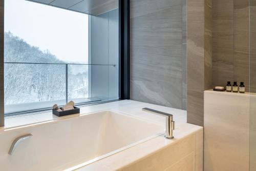 a bath tub in a bathroom with a window at Park Hyatt Niseko Hanazono in Kutchan