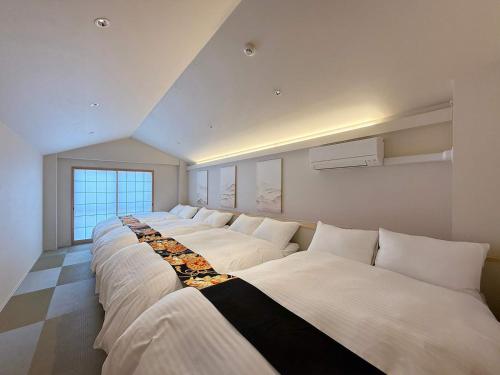 a row of white beds in a room at b hotel Miyajima Omotesando - Sacred Island Stay 31 in Miyajima