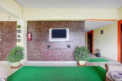 a living room with a tv and green carpet at Super Collection O Summanahalli Bus Stand Formerly Elevate 58 in Bengaluru