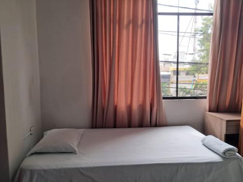 a bed in a room with a window at Hospedaje bolognesi in Piura