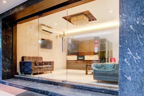 a room with a glass window with a couch and chair at Super Townhouse Guwahati Railway Station Formerly Niharika Guest House in Guwahati