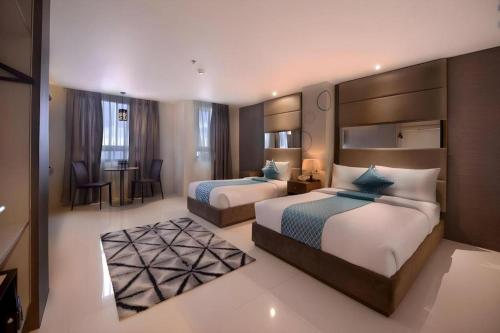 a hotel room with two beds and a desk at Hotel Estrella in Tacloban