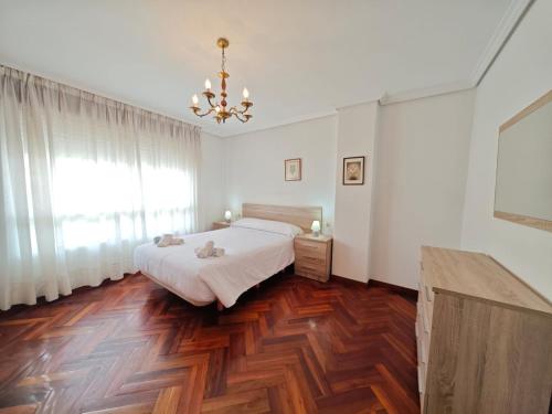 a bedroom with a bed and a chandelier at Panxon, Arquitecto Palacios, piso con terraza in Nigrán