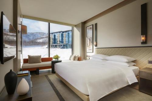 a bedroom with a large white bed and a large window at Park Hyatt Niseko Hanazono in Kutchan