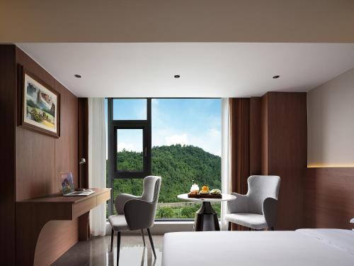 a bedroom with a large window with a table and chairs at 张家界叁禾溪居-Free one way pick up service over 2 nights in Zhangjiajie