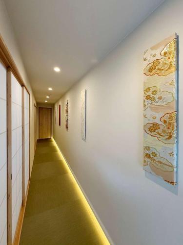 a hallway with a yellow floor and paintings on the walls at b hotel Miyajima Omotesando - Sacred Island Stay 32 in Miyajima
