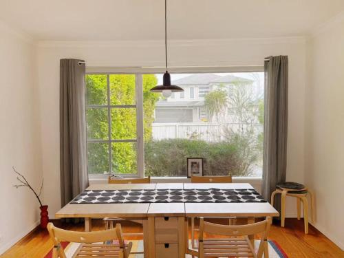 a dining room with a table and a large window at Bright & Breezy Stay by the sea in Bonbeach