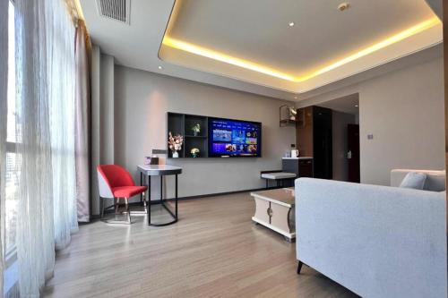 a living room with a couch and a tv on the wall at Yitel Collection Lianyungang High-speed Railway Station Suning Plaza in Lianyungang