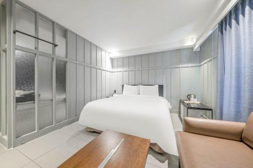 a bedroom with a white bed and a couch at Aloha Hotel in Hanam