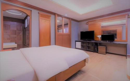 a bedroom with a white bed and a television at Hotel Head-One in Uijeongbu